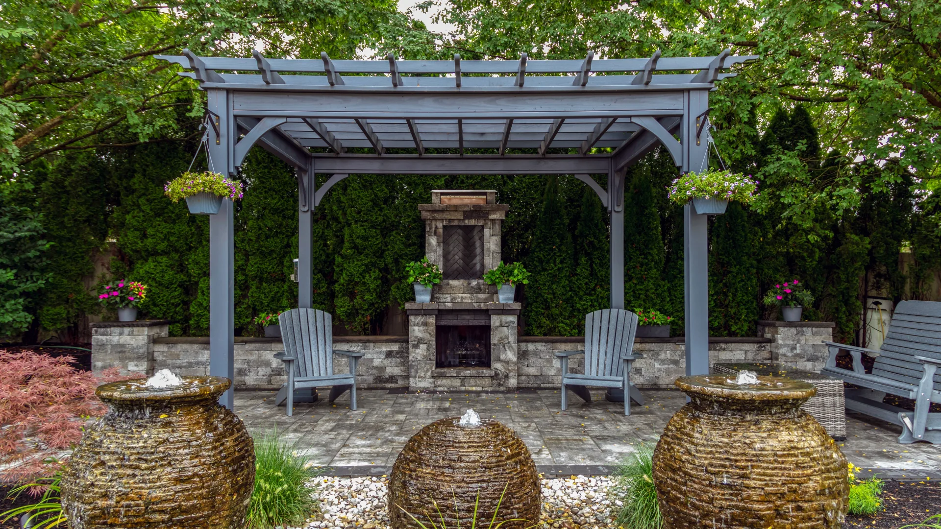 Traditional wood pergola over a paver patio with a stone fireplace and seating