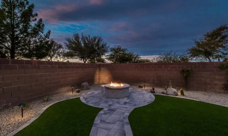 Fire pit on a paver patio with low-voltage path lights at dusk